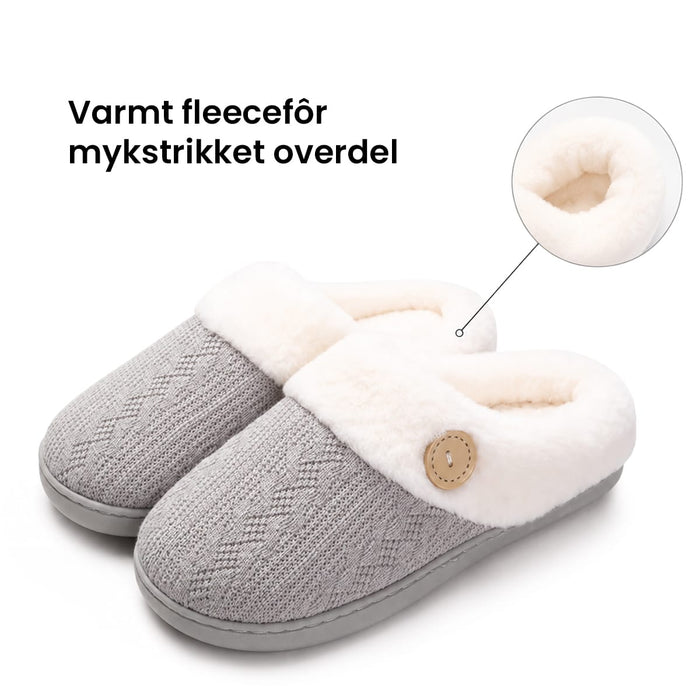 Grå, varmt fôrede tøfler med hvitt fleecefôr, knappelukking på siden, sklisikker såle og strukturert innside.