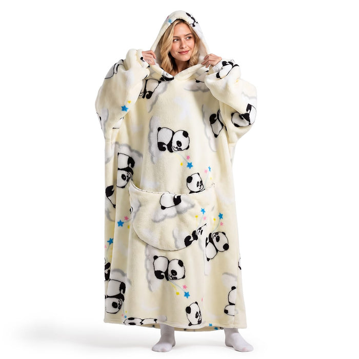 En smilende kvinne i en myk, oversized hettegenser med pandamotiv og romslig lomme holder fast i hetten.