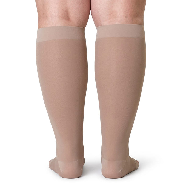 Baksiden av et ben med beige kompresjonsstrømper for leggene, plussstørrelse, 20–30 mmHg, mot hvit bakgrunn.