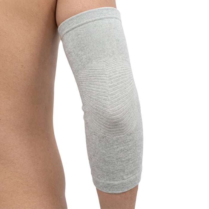 En person har på seg en lysgrå albuestøtte i bambus som dekker albuen og overarmen, sett fra siden.