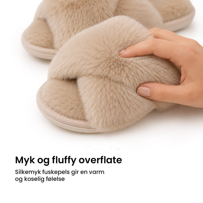 En hånd berører de beige, krysslagte remmene i fuskepels på de myke vintertøflene.
