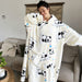 En kvinne smiler i en oversized fleecegenser fra Kroppsbutiken, omgitt av beige innredning i stuen.